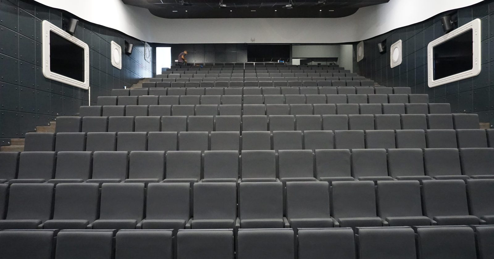 Pusta sala posiedzeń z rzędami krzeseł zwróconych ku podium — miejsce, w którym zbierają się organy spółki