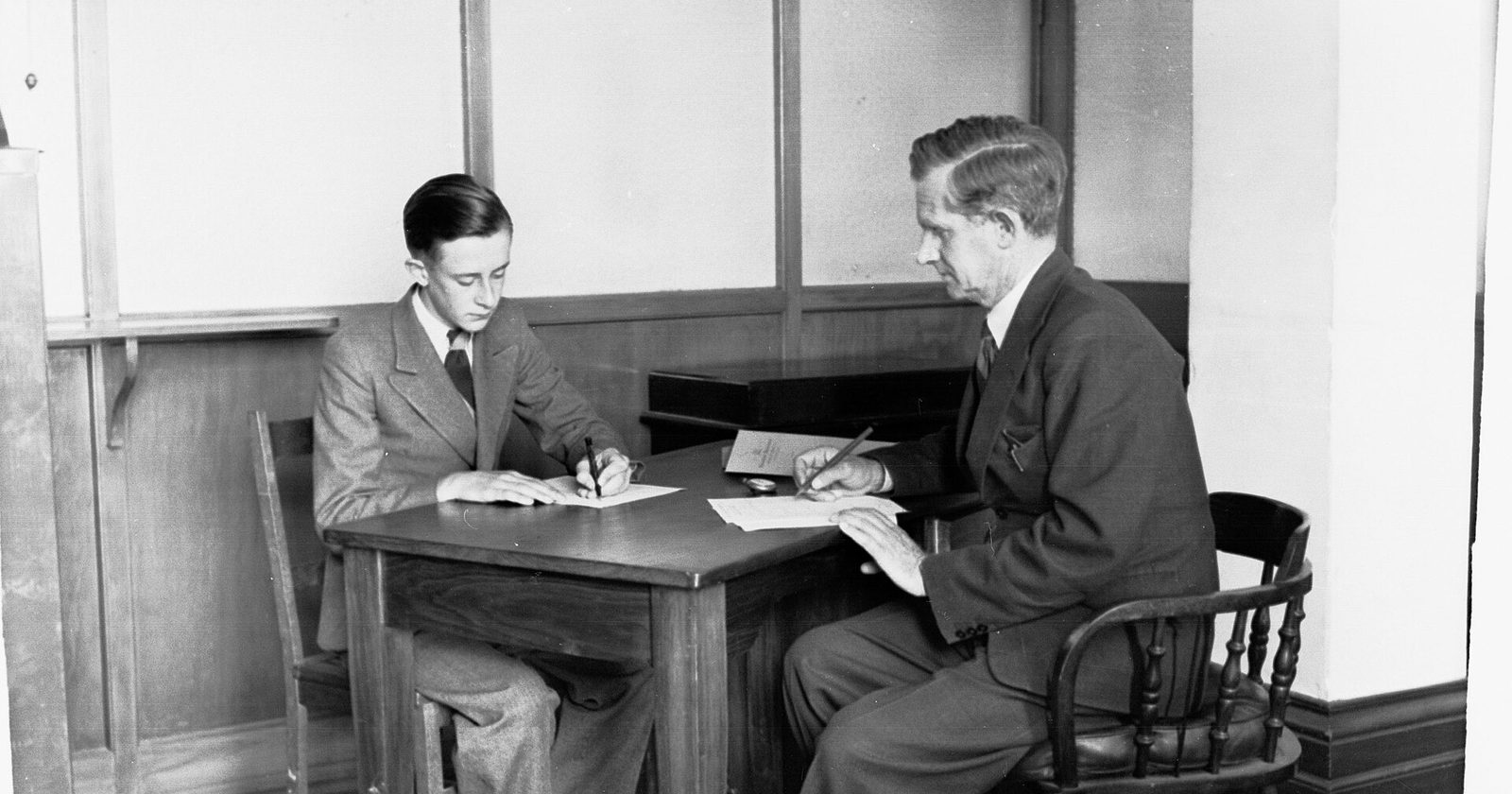 Psycholog rozmawia z młodym pacjentem przy biurku w gabinecie — archiwalne zdjęcie poradni psychologicznej